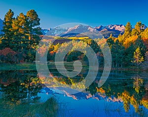 San Juan Range and fall color reflects in Colorado pond
