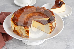 San Sebastian cheesecake on top on a white plate on a gray concrete background. Traditional Spanish dessert. photo