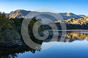 Sanabria Lake Natural Park in autumn at sunset with the mountains reflected in the water, Zamora, Castilla y LeÃ³n, Spain