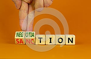 Sanction or negotiation symbol. Businessman turns cubes, changes the word sanction to negotiation. Beautiful orange table, orange