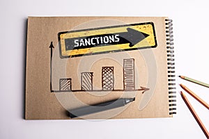Sanctions Concept. Notepad development chart and arrow with text. White office desk
