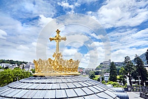 Sanctuary of Lourdes. Dome of The Basilica of Our Lady of the Rosary. The Golden Crown and the Cross. Blue sky with clouds