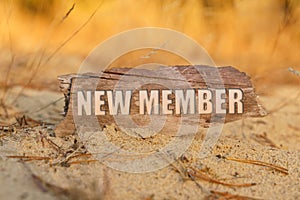 In the sand against the background of yellow grass there is a sign with the inscription - NEW MEMBER