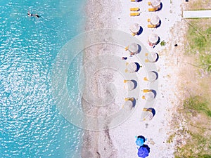 Sand beach in Greece aerial view with umbrellas and sun chairs