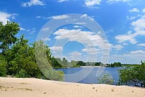 Sand beach on river with green trees