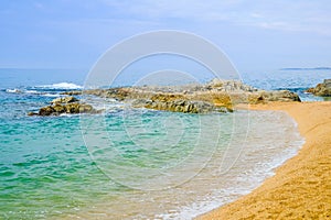 Sand beach with rocks in cloudy weather in Lloret de Mar, Costa Brava, Spain. Concept of rest