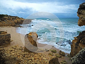 sand beach with rough sea waves and sandstone formation beautiful sandstone cliffs and blue sky background in Algarve Portugal