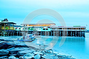 The sand beach and sea with fishing boat that parked on the beachfront with rock and reef in morning with sunrise