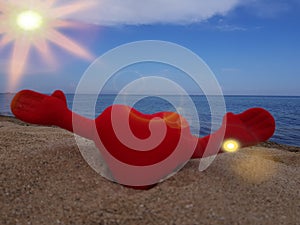 on the sand on the beach , a toy red soft heart holds its hands to the sides . Christmas on the beach.