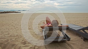 Sand Beach with Woman on Folding Chair Looks at Sea