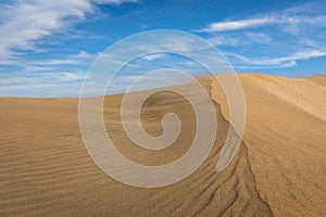 Sand in the Dunes of Maspalomas, a small desert on Gran Canaria, Spain. Sand blowing in the wind on top of the hill.