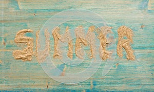 Sand on blue planked wood with the word Summer. Background with copy space. Top view