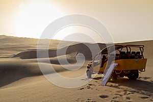 Sand boarding ,Dune Buggy parked in the desert during sunset at Huacachina Oasis in Ica, Peru