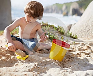 Sand castle, beach and child with bucket and toys on summer holiday, vacation and relax by ocean. Childhood, building or