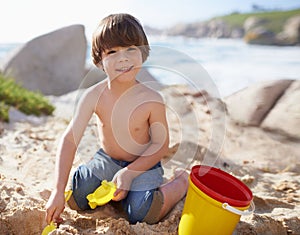 Sand castle, beach and portrait of child with bucket and toys on summer holiday, vacation and relax by ocean. Childhood