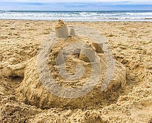 Sand castle building with towers on the beach with view on the sea