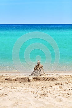 Sand castle and crocodile sculpture on beach, summer holiday con