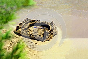 Sand castle on the seashore. Children`s building of sand on the beach sea. Ð¡hild built a castle on seacoast