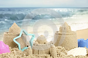 Sand castles with toys on ocean beach, closeup. Outdoor play