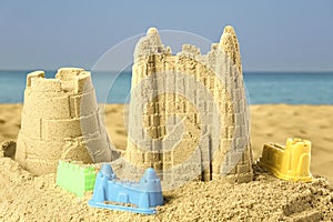 Sand castles with toys on ocean beach. Outdoor play