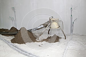 Sand and cement floor screed. Construction site - machine floor screed and electic wires
