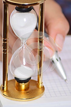 Sand clock and female hand with pen