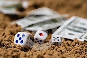 In the sand, dice, a few dollars in the background