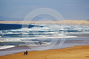 Large sand dunes and wild waves at Australian beach with horse cart