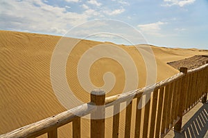 Sand dunes behind a wooden fence.