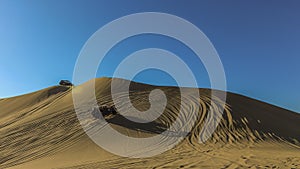 Sand dunes and buggies against blue sky at Huacachina, Peru