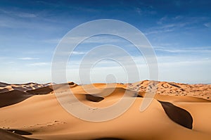 Sand dunes. Desert landscape. Erg Chebbi in Morocco. Sahara desert. Vast desert landscape with endless dunes and blue sky in the