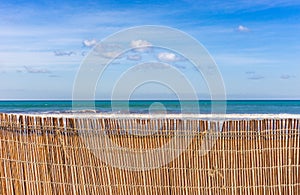 Sand dunes fence at beach with sea water and sky background