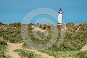 The sand dunes, and the grade II listed building Point of Ayr Lighthouse at Talacre beach in Wales on a sunny summer day photo