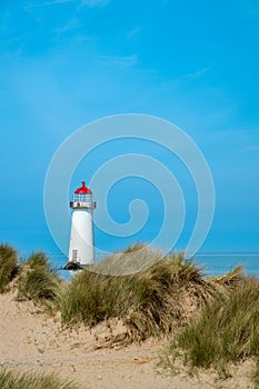 The sand dunes, and the grade II listed building Point of Ayr Lighthouse at Talacre beach in Wales on a sunny summer day photo