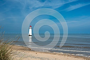 The sand dunes, and the grade II listed building Point of Ayr Lighthouse at Talacre beach in Wales on a sunny summer day photo