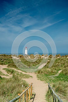 The sand dunes, and the grade II listed building Point of Ayr Lighthouse at Talacre beach in Wales on a sunny summer day