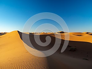 Sand dunes in Morocco, desert landscape, sand texture, tourist camp for night stay, panorama view of sunset over Sahara