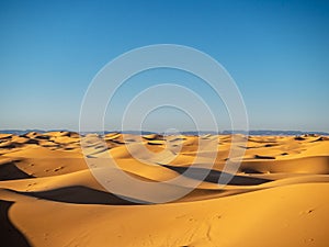 Sand dunes in Morocco, desert landscape, sand texture, tourist camp for night stay, panorama view of sunset over Sahara