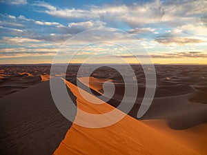 Sand dunes in Morocco, desert landscape, sand texture, tourist camp for night stay, panorama view of sunset over Sahara