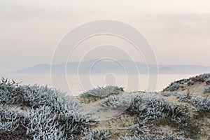 Sand dunes with sea and mountains on the background in Milos island, Greece