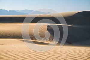 The sand dunes during sunset and strong wind. Summer landscape in the desert. Hot weather.