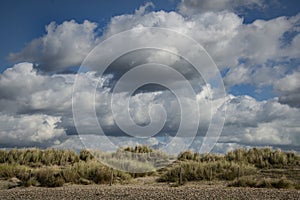 Sand dunes underneath a blue cloudy dramatic sky.