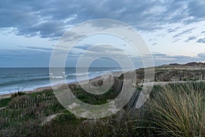 Sand dunes and waves breaking on an endless beach under a stormy sky