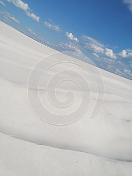 Sand dunes of white sand. A desolate landscape with blue skies and bright sunshine