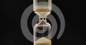 Sand falls through a bottleneck In a hourglass.