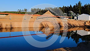 Sand mining. Equipment for sand extraction on the shore of the pond in a sand quarry in a pine forest.