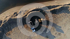 Sand mining industry, sand mine at the quarry. Scene. Aerial top view of a bulldozer machine putting sand to the truck