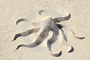 Sand octopus sculpture in white beach