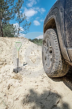 sand off-road concept. shovel near suv car wheel