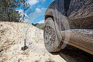 sand off-road concept. shovel near suv car wheel